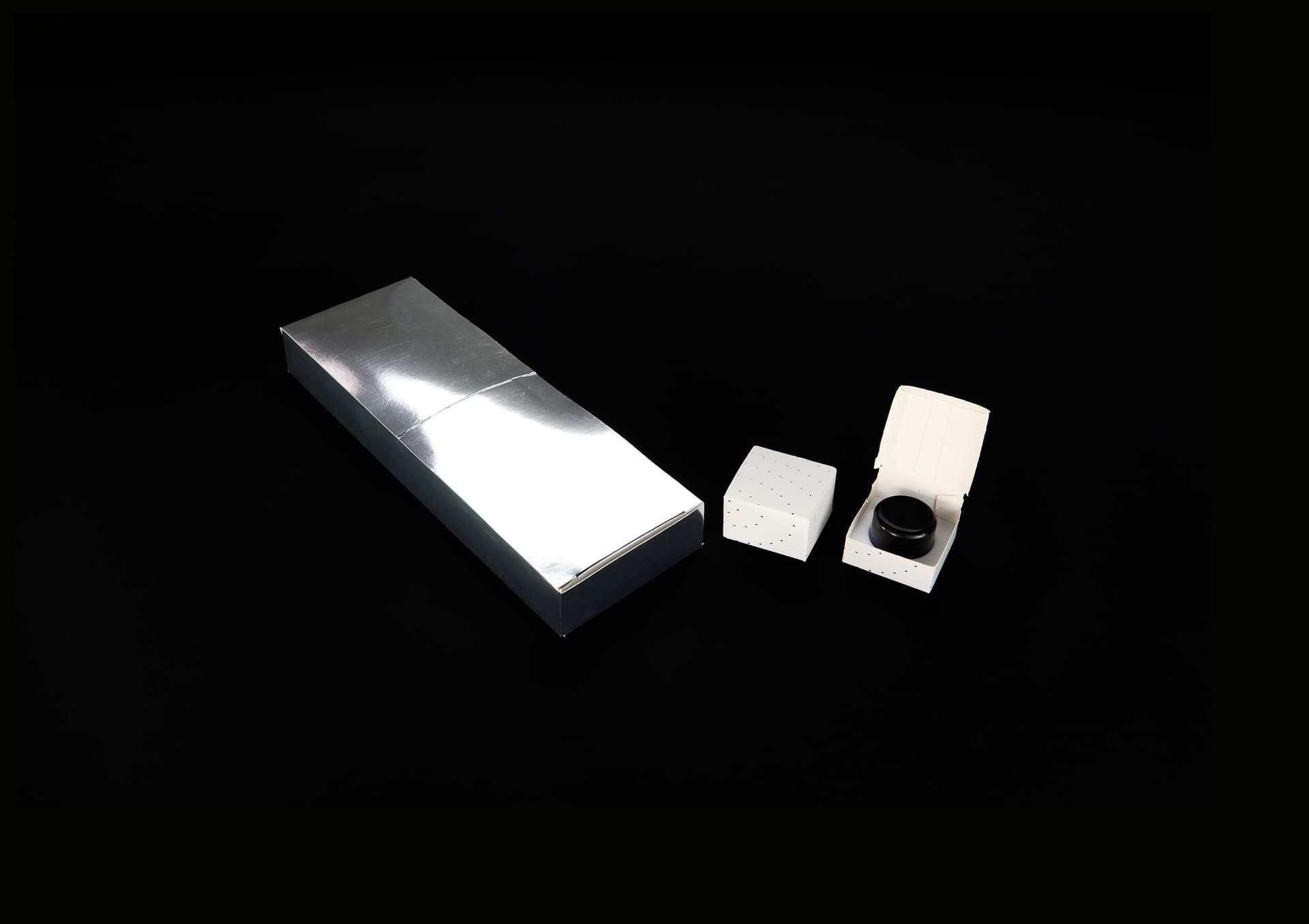 Silver metallic parent carton with white concentrate boxes and black jar