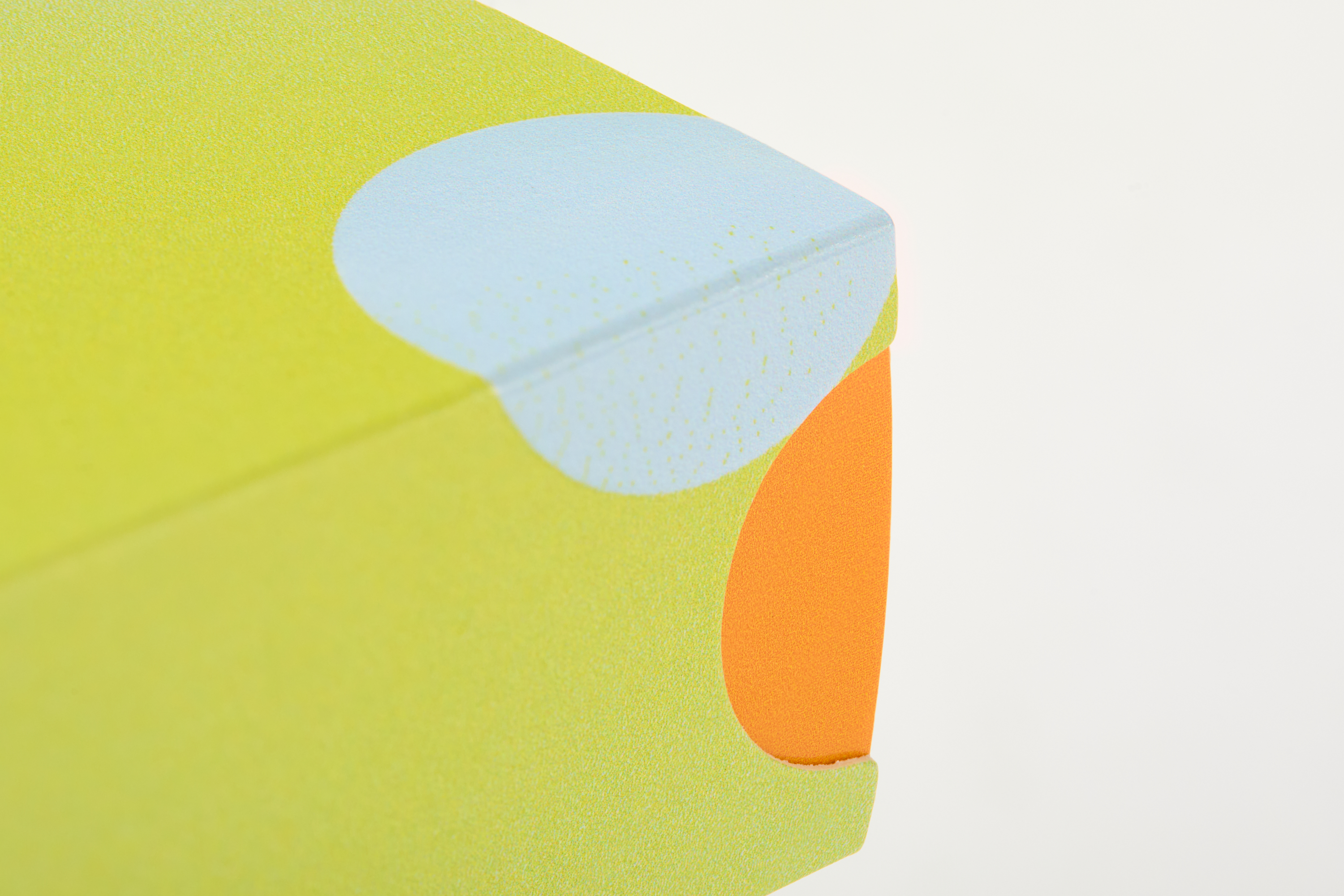 Close-up corner detail of concentrate slide box with green sleeve, blue dot, and orange tray